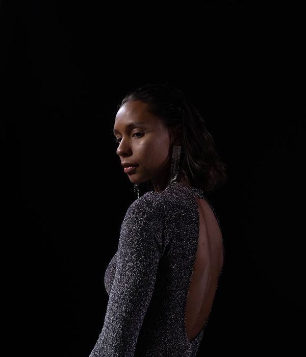 Woman in a calm yoga pose in a dark studio with honey-colored light.